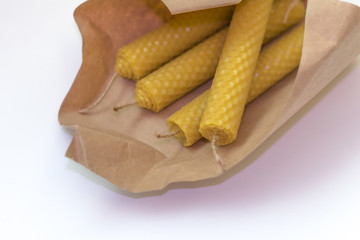 Wax candle and flowers. Magic, witchcraft background. Halloween rolled the candle. Handmade beeswax. Yellow tulips and craft wrapping aged paper. Environmental friendliness. eco friendly