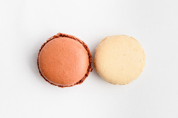 Top view of two sweet vivid brown chocolate and white vanilla French macaron isolated on white background, tasty French dessert on a table