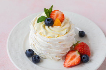 Pavlova meringue cake with fresh berries on pink background
