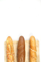 three baguettes on a cutting board on white background flat lay. Vertical image