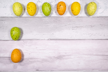 green and orange yellow easter eggs on a background of old wooden boards resembling old parquet. Easter concept