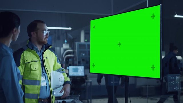 Office Meeting: Confident Female Project Manager to Chief Engineer, Watching Interactive Digital Whiteboard TV that Shows Green Screen Chroma Key Display. Factory with Machinery. Slow Motion Gestures