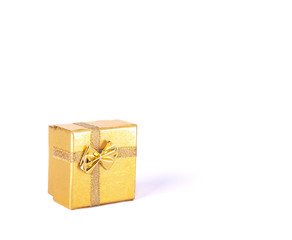 Gift box for jewelry gifts of gold color with a strip and a bow on a white background isolated