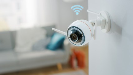 Close Up Object Shot of a Modern Wi-Fi Surveillance Camera with Two Antennas on a White Wall in a...