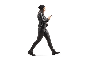 Woman in leather clothes walking and looking at mobile phone