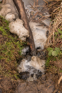 Little spring with flowing and foamy water along the ground