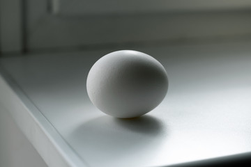 Egg on a white kitchen table. Raw chicken egg
