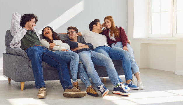 A Group Of Friends Is Sitting On Couch In A Room On A Gray Background.