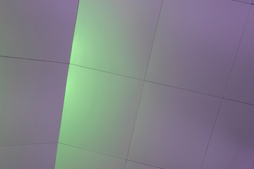 Background image. Building interior wall highlighted with light rays into purple and green.