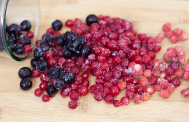 frozen berries. raspberries, black and red currants. on a wooden table
