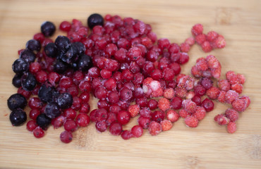 frozen berries. raspberries, black and red currants. on a wooden table