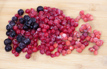 frozen berries. raspberries, black and red currants. on a wooden table