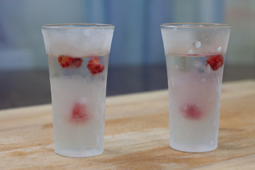 ice-cold vodka glasses with raspberries and currants on a wooden stand