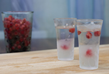 ice-cold vodka glasses with raspberries and currants on a wooden stand