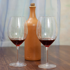 a bottle of homemade wine with two glasses on the table