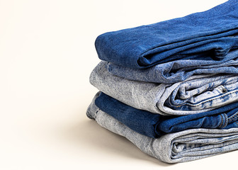 A stack of light and dark jeans on the white background. Jeans background, texture denim, copy space