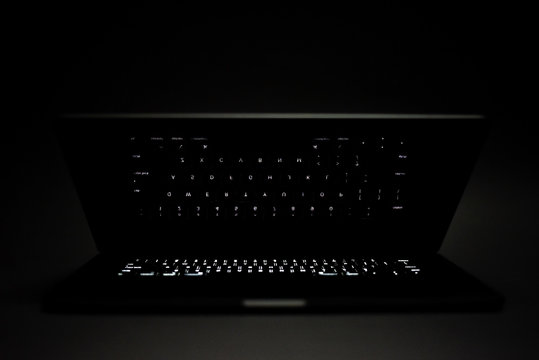 Apple MacBook Pro laptop with glowing keyboard shown isolated on dark background on March 14, 2020 in Calgary, Alberta.