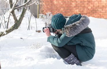 Girl photographer with a camera in winter.  Squatting and taking pictures