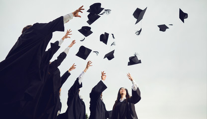 A group of graduates throws hats up into the sky.