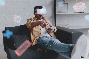 Young smiling man in VR glasses playing game using joystick, virtual reality © Epic_pic