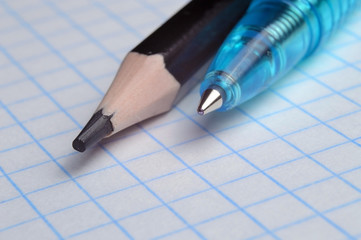 pencil and ballpoint pen on a squared notebook. close up