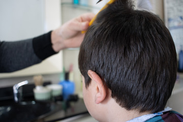 Obraz na płótnie Canvas Cheerful Caucasian boy getting hairstyle in barbershop.