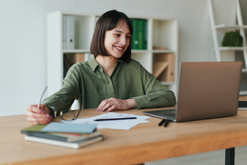 Closeup cropped portrait of smiling girl using laptop in minimalist co-working