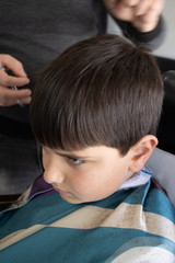 Obraz premium Cheerful Caucasian boy getting hairstyle in barbershop.