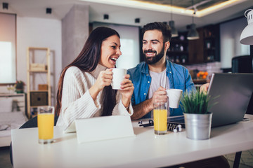 Happy couple doing business together working at home on the laptop.