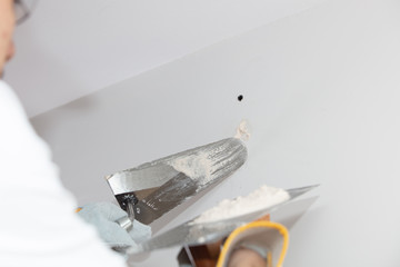 Plasterer home improvement handyman worker with putty knife working on apartment wall filling