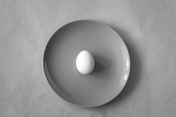 Egg on a plate in grey monochrome mode, Easter minimalistic concept