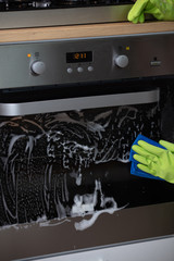 Man's hand cleaning the kitchen oven