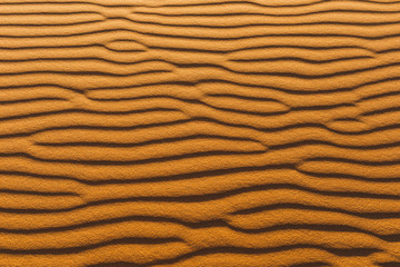 Orange texture of sand dune. Abstract shape, background, shadow and sun light. Sahara desert.