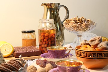 On the table there are sweets: cake, dry fruits, nuts and jam side view