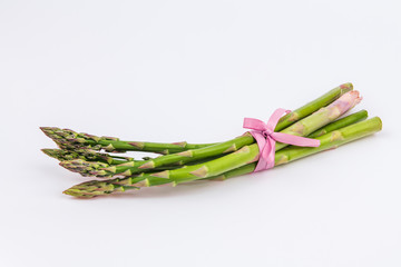 Bunch of fresh raw garden asparagus isolated on white background. Green spring vegetables. Edible sprouts of asparagus