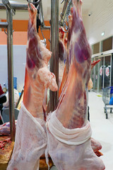 open warehouse, hanging hooks of frozen lamb carcasses. Halal cut.
