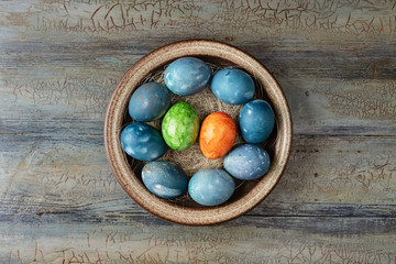 Different easter eggs in bowl on a wooden background