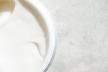 Close-up opening face cream in container on marble background with copy space, top view. Cosmetology detail