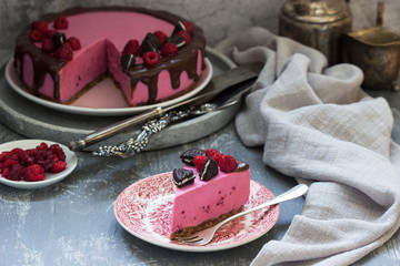 Currant mousse cake decorated with pieces of oreo cookies and raspberries.