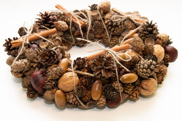 Fototapeta na wymiar Decorative wreath of natural cones of cinnamon acorns chestnuts on a white background
