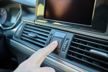 A man in a modern car. Hand presses the emergency button to turn on the alarm.