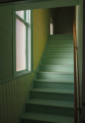 Green and yellow hallway with stairs and window