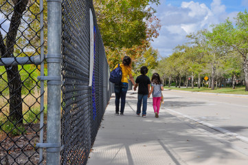 coronavirus kids school empty mom boy girl kids holding hands fence closeup pathway exterior pavement