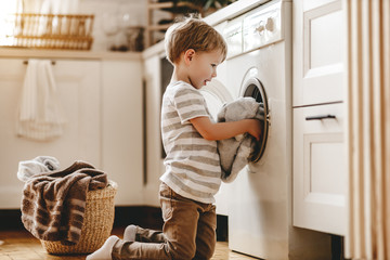 happy  householder child boy in laundry   with washing machine