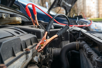 Fototapeta premium Jump cables on car low power battery. Broken car start attempt. Selective focus.
