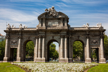 Fototapeta na wymiar The famous Puerta de Alcala on a beautiful sunny day in Madrid City. Inscription on the pediment: Rey Carlos III year 1778