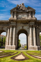 Fototapeta na wymiar The famous Puerta de Alcala on a beautiful sunny day in Madrid City. Inscription on the pediment: Rey Carlos III year 1778