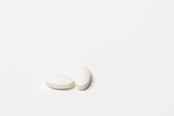 Two white tablet oval shaped on a white background. Isolated