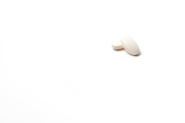 Two white tablet oval shaped on a white background. One lies on the other on top. Isolated