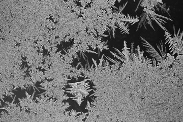 Crystal ice condensation patterns on a frosty glass window pane